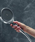Hand holding Rainfinity 5-Inch Handheld Shower Head With Three Spray Modes PowderRain Intense PowderRain MonoRain Chrome Finish