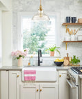 Kitchen with Brass Gold Glass Dome Pendant Light above sink, featuring clear handblown glass, showcasing sleek modern design.