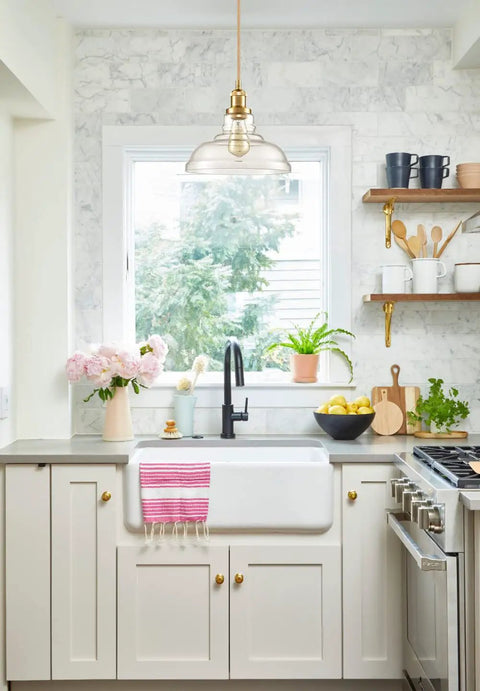Kitchen with Brass Gold Glass Dome Pendant Light above sink, featuring clear handblown glass, showcasing sleek modern design.