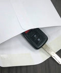 Front view of white 6x9 in key drop envelope with gummed seal and car key for scale