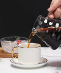 Pouring coffee from a glass carafe into a white cup on a saucer, with ice bowl in background, Smooth Sippin Cold Brew Drip Coffee Maker With Stainless Filter And Adjustable Flow Yields Barista Style Drinks Via Glass Carafe On Acrylic Stand Makes 3 To 6 Cups Major Upgrade For Coffee Crew Seeking Dope Routines.