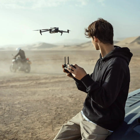 Person controlling Mavic 3 Cine Premium Drone Kit With Hasselblad 4/3 CMOS Camera in desert near motorcyclist