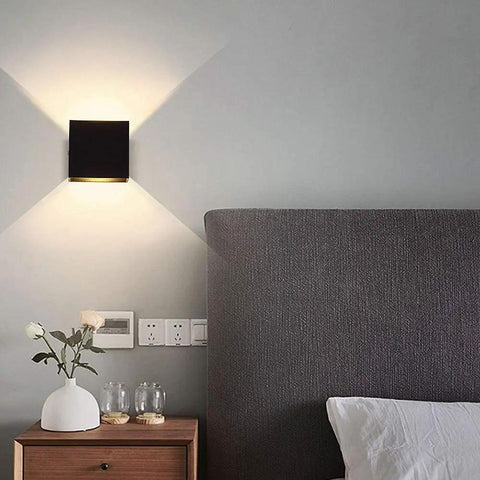 Bedroom setting with Dimmable 10W LED Indoor Wall Sconce in Black Finish, modern square design, casting up and down warm white light.