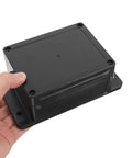 Person holding a black Waterproof Electrical Junction Box Enclosure 115x90x55mm with mounting ear for power wiring.