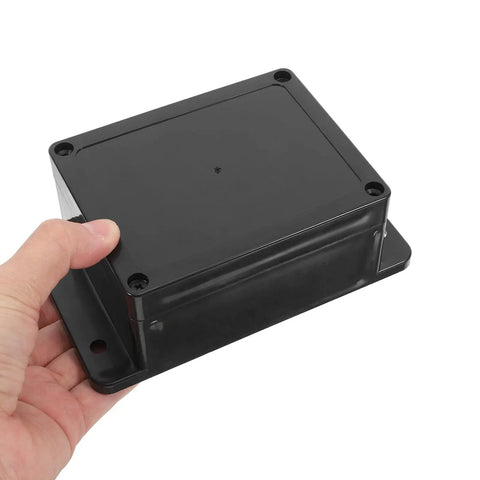 Person holding a black Waterproof Electrical Junction Box Enclosure 115x90x55mm with mounting ear for power wiring.