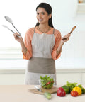 Woman in kitchen holding utensils with stainless steel frying tongs