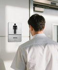 ADA Braille Restroom Sign Set 9 By 6 Inches Self Adhesive Silver Two Pack For Men And Women Bathroom Door Signs High Contrast Graphics Durable Office And Public Restrooms No Fuss Install on a men's restroom door