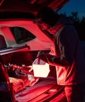 Person using 2 In 1 Solar Camping Lantern And Phone Charger With 300 Lumens Of Bright LED Light, Red Night Mode, Turbo Boost outdoors