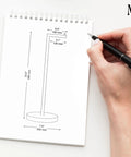 Person sketching Free Standing Toilet Paper Holder Stand For 4 Rolls In Matte Black Stainless Steel, with dimensions on paper.