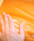 Crystal Clear Duct Tape 1.88 Inch By 5 Yard Heavy Duty All Purpose Tape applied on orange surface, sealing a tear.