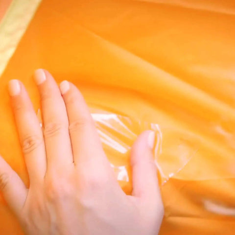 Crystal Clear Duct Tape 1.88 Inch By 5 Yard Heavy Duty All Purpose Tape applied on orange surface, sealing a tear.