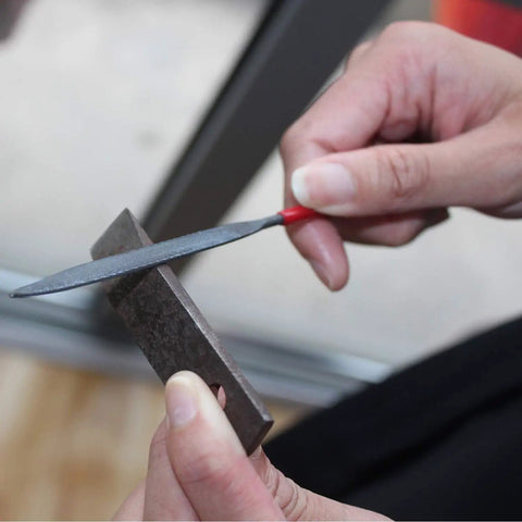 Using a mini file from the Ten Piece Needle File Set With Pro Grade Hardened Alloy Steel Mini Files Including Tapered Round Half Round Barrette Crossing Knife Warding Square Three Square Five And A Half Inch Length Dipped Handles And Dust Free PVC Pouch For Easy Metal Shaping on metal surface