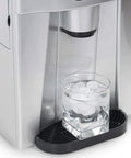 Zero Drama Automatic Countertop Ice Machine Cranking Out Fresh Clear Cubes At Nine Point Five Kilograms Daily With Food Grade Abs Body And Sleek Brushed Metal Finish For Instant Home Bar Ready Vibes, glass filled with ice under dispenser.