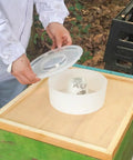 Person using Four Pack Round Bee Feeders For Hives Top Water Or Syrup Dispenser, Clear Lid Beehive Top Feeder, 3.1L Capacity