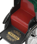 Close-up of vintage red zinc alloy rickshaw model toy's seat and detailed black frame. Perfect for desk decor.