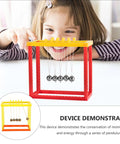 Child playing with a Newton Cradle Balance Ball Science DIY Assembly Educational Physics Experiment Desk Decor For Home Office Study Nerdy Desk Toy That Demonstrates Momentum And Conservation Of Energy.