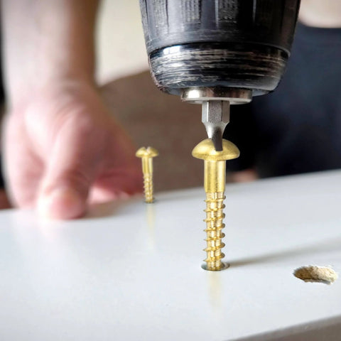 Brass Round Head Wood Screws M3 X 25mm Slotted Self-Tapping being installed into wood with a drill, close-up view.