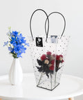 Flower Bouquet Wrap Bag With Handle For Easy Carry And Display, Plastic Rose Packaging Bag next to blue flowers in a vase.