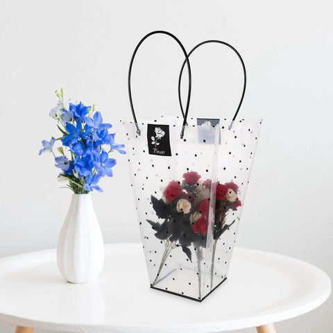 Flower Bouquet Wrap Bag With Handle For Easy Carry And Display, Plastic Rose Packaging Bag next to blue flowers in a vase.