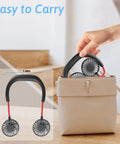 Woman placing Neck Wearable Portable Fan With 2500mAh Battery USB Rechargeable Hands Free Dual Head Rotatable Mini Face Cooling Personal Fan into a beige handbag