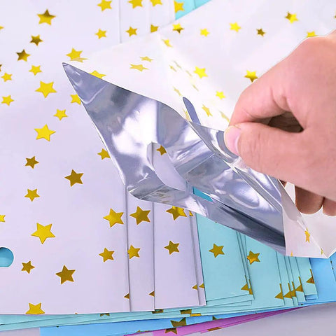 Hand holding a star-patterned foil bag from 40 Pack Party Favor Bags Goodie Bags For Birthday Parties And More, Bulk Gift Bags