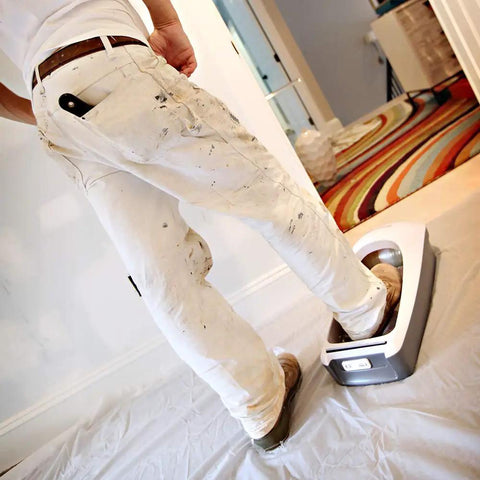 Person using EZ Floor Guard Starter Kit With Heavy Duty 2.45 Mil Film while painting, shoe cover dispenser in use.