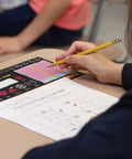 Student using Top Shelf Chalkboard Style K-2 Desk Reference Mats for math practice on a desk.
