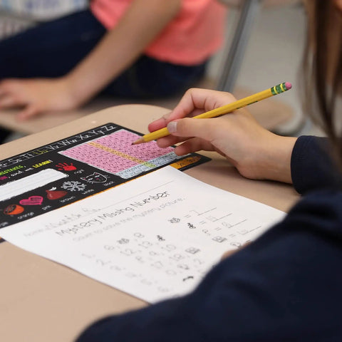 Student using Top Shelf Chalkboard Style K-2 Desk Reference Mats for math practice on a desk.