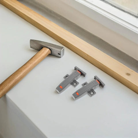 Heavy Duty Push Door Catch Kit for Cabinets and Pantry on table beside a hammer