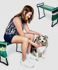 Woman using Dog Grooming And Bath Bench For Sit Or Kneel Comfort, Foldable Portable Pet Grooming Bench With Cushioned Seat and handles.