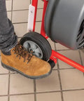 Person's foot operating the wheel of the Heavy Workhorse 115 Volt Drain Cleaning Machine With Auto Feed Cable Control.