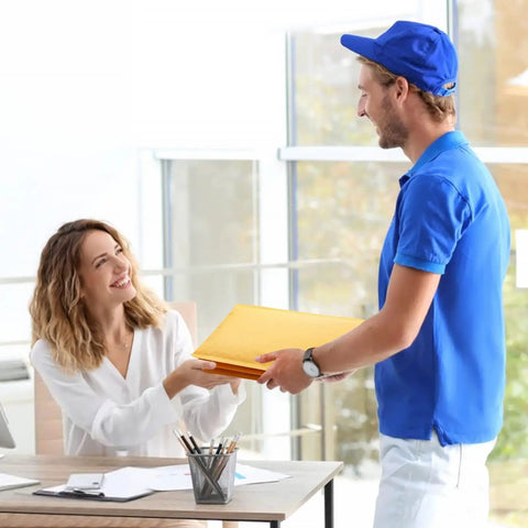 Smiling woman receiving 50 Pack Bubble Mailers 4x8 Inches Self Seal Kraft Poly Padded Envelopes from man in blue uniform in office setting