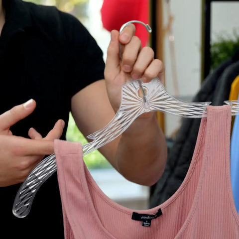 Person holding Heavy Duty Plastic Clothes Hangers Set Of 12 For Wardrobe Organization, displaying clear hanger with tank top.