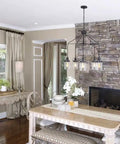 Dining room with stone wall, white table, and modern ceiling light fixture for entertaining, featuring Topsail three light inverted pendant.