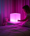 Child with Rechargeable 12 Inch LED Light Cube Stool With Remote Control Mood Lamp Soothing Night Light For Home Patio Kids Room And Nursery 16 Color Options 4 Modes 8 Brightness Levels Color Changing Decorative Lighting on a nightstand