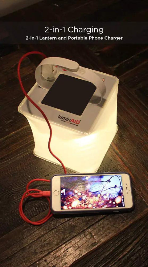 Two In One Solar Camping Lantern And Phone Charger Inflatable LED Light illuminating while charging a phone on wooden surface