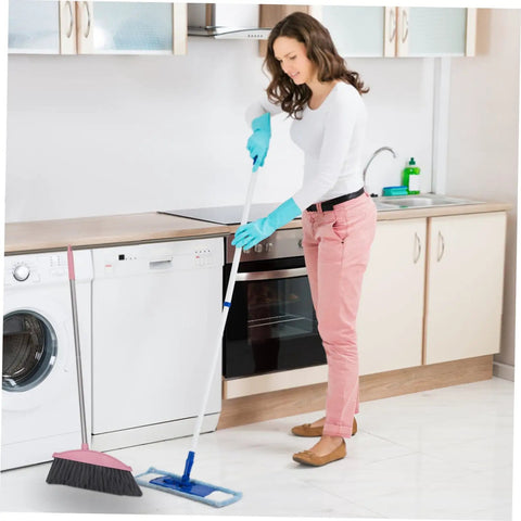 Heavy Duty Pink Broom With Extended Handle Sweeps Indoors And Outdoors in a kitchen, used by a woman in gloves on tiled floor.