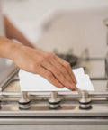 Person using Heavy Duty Kitchen Cleaning Wipes For Microwave Air Fryer Stove And Cooktops All Purpose Appliance Cleaner Cloths on stovetop.