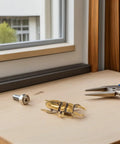 Two Piece Brass Beetle Drawer Knob Set For Dressers And Cabinets displayed on a wooden surface with tools nearby