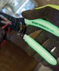 Glow In The Dark Grips Wire Stripper And Cutter With Serrated Curve Nose For 10 To 18 AWG Solid And 12 To 20 AWG Stranded Wire Pro Grade Tool Made In USA in use with glow handles visible.