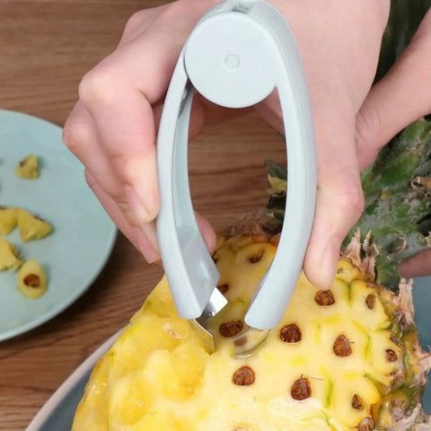 Hand using V Shape Fruit Core Remover And Strawberry Huller Stainless Steel Kitchen Gadget With Ergonomic Non Slip Handle Auto Rebound Spring for pineapple peeling