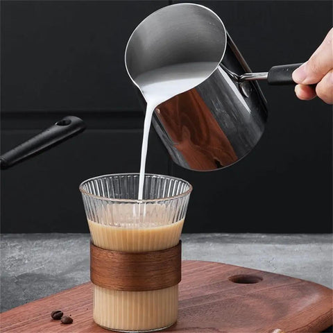 Stainless Steel Turkish Coffee Pot pouring milk into a glass on a wooden board, showcasing the durable kitchen vessel design.