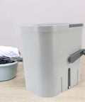No Fuss Portable Clothes Washer Game Changing Hand Crank Operation, compact gray laundry machine beside a laundry basket.