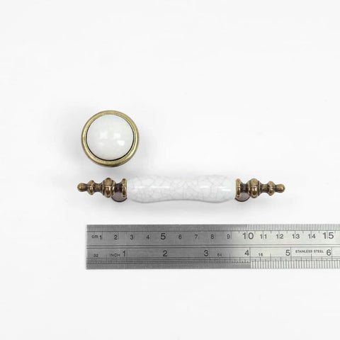 Slick Vintage Style Antique Bronze And White Crackled Ceramic Cabinet Pull And Knob Set Of Eight Pieces on ruler for scale.