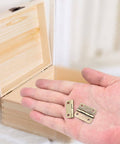 Hand holding Antique Bronze Mini Hinges 25x19mm with Wooden Jewelry Box in background