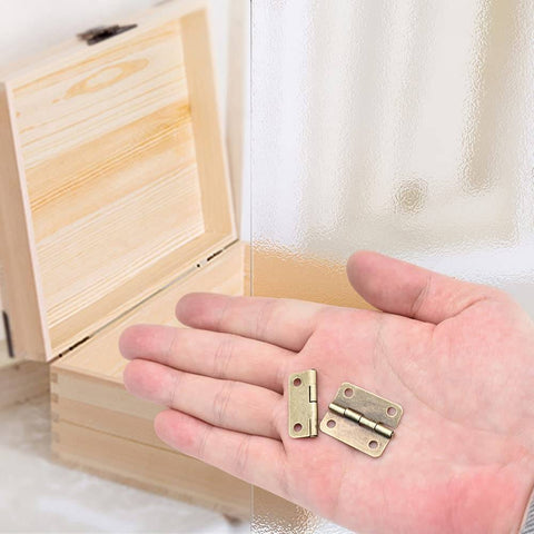 Hand holding Antique Bronze Mini Hinges 25x19mm with Wooden Jewelry Box in background