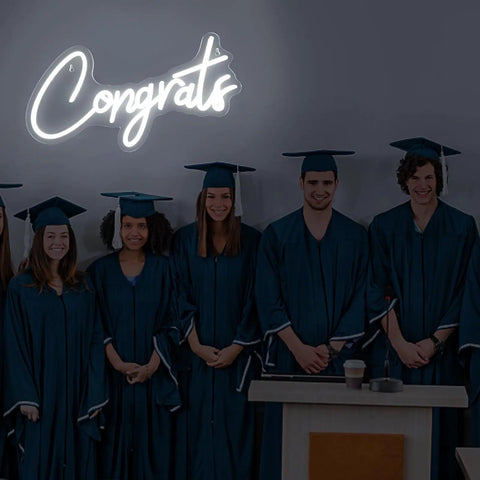White Congrats Neon Sign Dimmable LED Wall Art For Graduation Party And Wedding Backdrop 17.7 By 9 Inches with graduates under it.