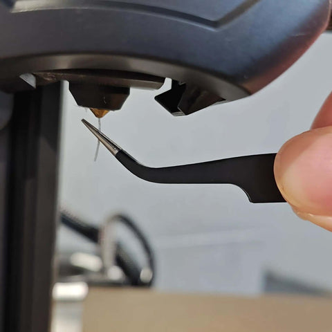 Using tweezers from the Complete 42Pcs 3D Printer Nozzle Cleaning Tool Kit for extruder maintenance on a 3D printer.