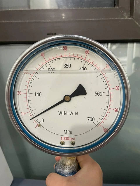 Front view of WIN-WIN waterjet high-pressure gauge showing MPa scale and 1000 psi label, held by hand