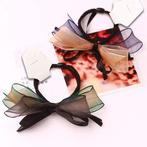 Two hair accessories with bows on white kraft jewelry display cards with hole for retail display and packaging.